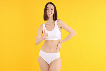 Obraz premium Concept of weight loss with slim young woman on yellow background