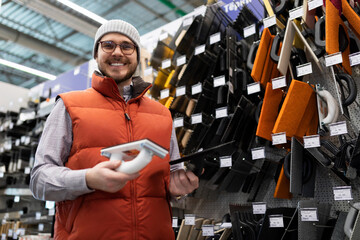a male builder in a hardware store buys a tool for wall plastering