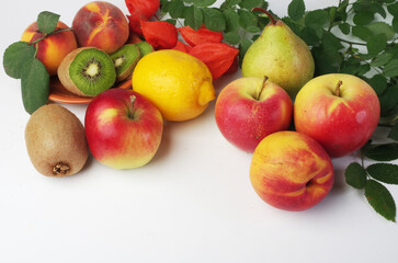 Fresh fruits apples, peaches, kiwi and leaves on a white background.