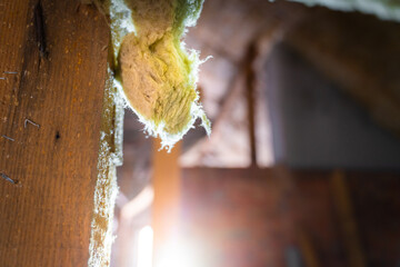 A piece of mineral wool hangs close-up in the backlight on the background of a construction site