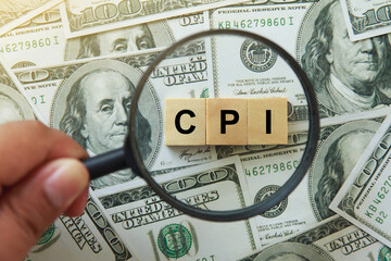 CPI, consumer price index symbol. hand holding magnifying glass investigating wooden block with words CPI, consumer price index on dollar bills. Business and CPI, consumer price index concept. - obrazy, fototapety, plakaty