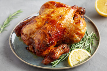 Homemade Lemon and Herb Rotisserie Chicken on a Plate on a gray background, side view.