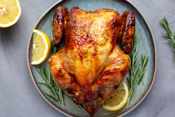 Homemade Lemon and Herb Rotisserie Chicken on a Plate on a gray background, top view. Close-up.