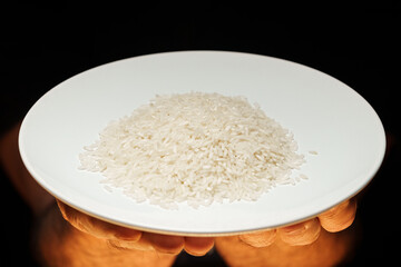 Hands holding a heap of dry rice grain on black background