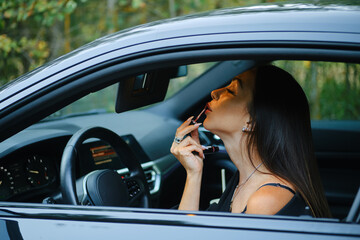 Naklejka premium Woman applying lipstick while sitting in the car
