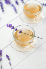 Cup with lavender tea and lavender flowers on wooden backgorund.
