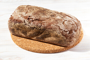 Freshly baked bread on a round board on a white wooden background