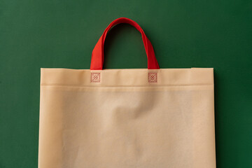 Textile shopping bag on green background flat lay