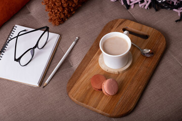 Autumn mood background with cup of cocoa, plaid and notepad on sofa. Hot drink in autumn concept