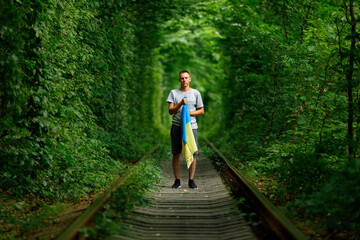 man raised his hands and holds the Ukrainian flag behind his back. concept Ukrainian patriot, rally in support of Ukraine