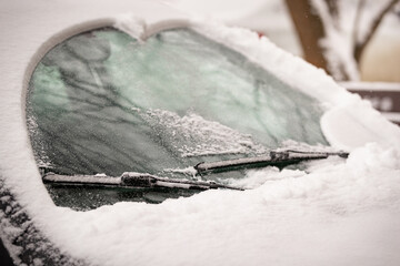 Wiper blades clean the icy windshield of the car from snow - winter, snowstorm, icing vehicle after...