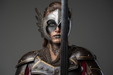 Antique female knight dressed in steel armor holding sword near her face. - obrazy, fototapety, plakaty