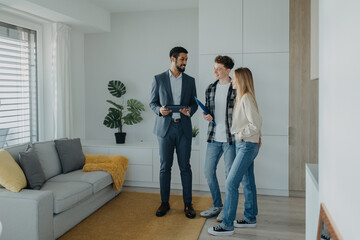 Happy young couple buying their new home and meeting real estate agent in apartment.