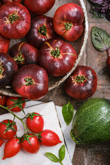 The harvest of assorted tomatoes, basil, spices, zucchini in a kitchen board. Colorful organic tomatoes on a dishes. Tomatoes different varieties. Organic vegetables fresh from market. Top view