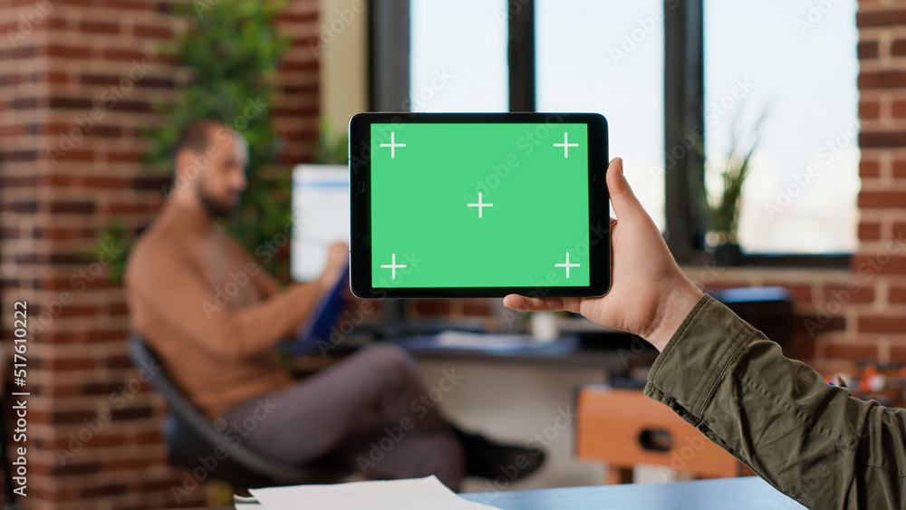 Poster male freelancer holding horizontal greenscreen on digital gadget, using tablet with blank mockup tem