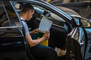 Man sitting in the sar salon in the garage and checking something