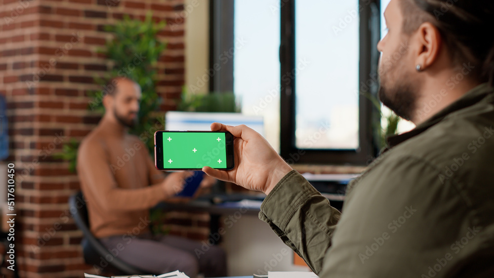 Poster Office employee looking at horizontal greenscreen on smartphone, analyzing isolated copyspace on template. Working with blank chroma key and mockup background on mobile phone. Tripod shot.