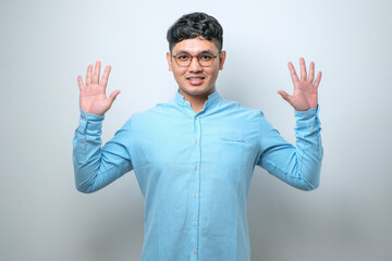 Naklejka premium Young asian man wearing casual clothes showing and pointing up with fingers number while smiling confident and happy