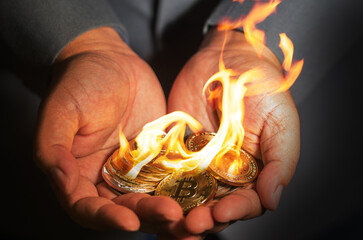Businessman showing cryptocurrency coins burning with flame on hand