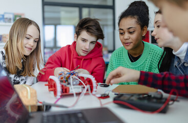 Group of high school students building and programming electric toys and robots at robotics classroom - obrazy, fototapety, plakaty
