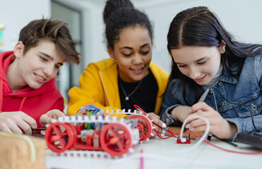Group of high school students building and programming electric toys and robots at robotics...