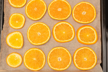 Fresh orange slices on oven tray ready for drying for handmade winter or Christmas decorations. Selective focus