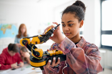 College student holding her robotic toy at robotics classroom at school.