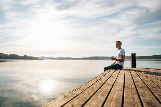 Man having coffee on pier by lake