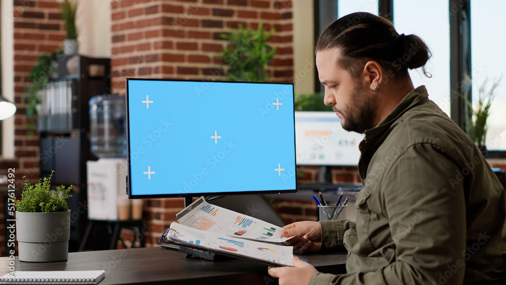 Poster company manager working with greenscreen mockup display on desktop computer, using blank copyspace t