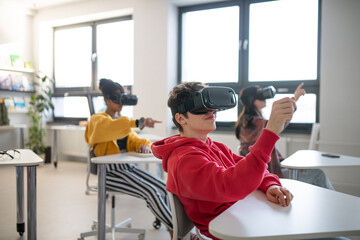 Teenage students wearing virtual reality goggles at school in computer science class