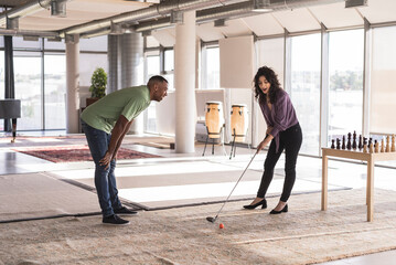 Happy businesswoman playing golf in office