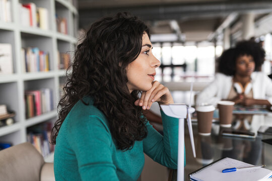 Businesswoman with wind turbine model sitting at desk