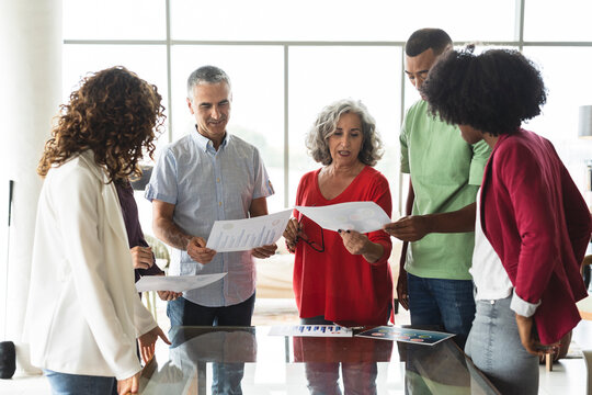 Smiling Business Colleagues Discussing Over Document In Office