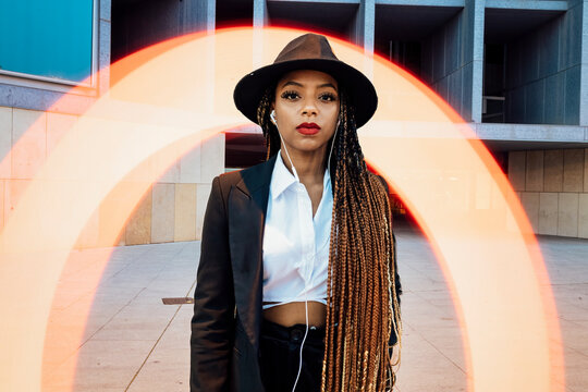 Young businesswoman standing in front of orange semi-circle light painting