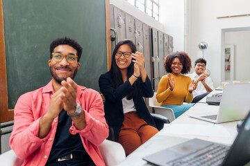 Happy multiracial colleagues clapping hands in office meeting