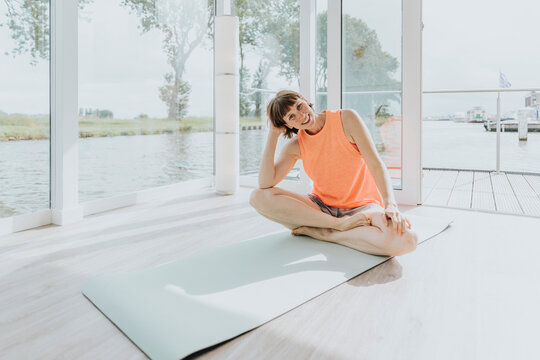 Happy Woman Sitting On Exercise Mat