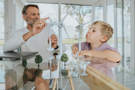 Happy father and son playing with wind turbine model - Powered by Adobe