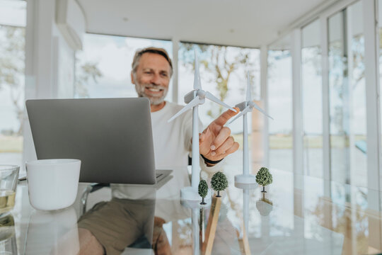 Happy freelancer with wind turbines sitting at table