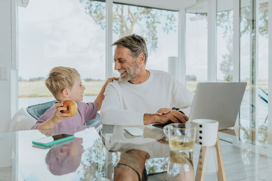 Happy mature man with son sitting at table