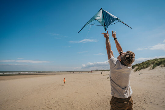 Man flying kite on sunny day at beach