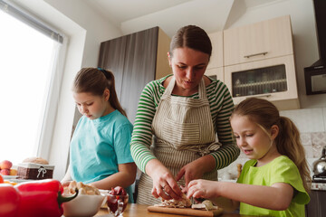 Mother helping daughter in preparing pizza at home