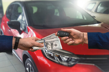 man hands over a large sum of dollars to another who in return passes the keys to a car bought