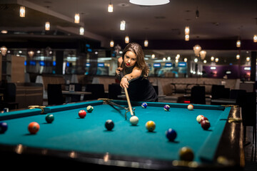 cheerful young woman playing billiard in pub