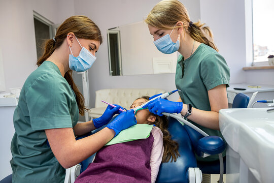 the dentist examine the child's teeth with a camera and display the picture on the screen.