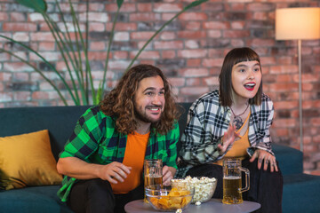 Pretty couple watching together in the evening on sport channel their favourite sport match they getting excited when favourite team getting the victory