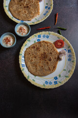 Indian breakfast item aloo paratha or potato stuffed flatbread served. Top view, selective focus.