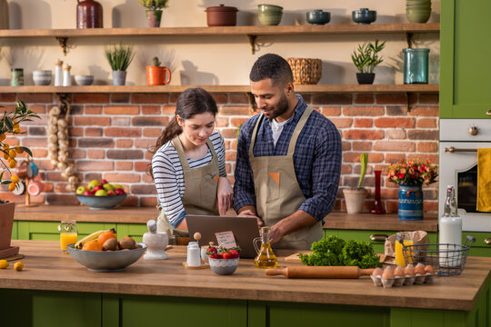 Large modern kitchen island excited with a large smile couple multiracial cut some fresh fruits to prepare the healthy breakfast together they discussing and feeling happy - Powered by Adobe