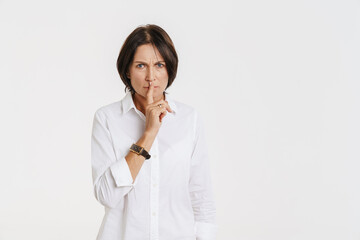 Mature brunette woman showing silence gesture at camera