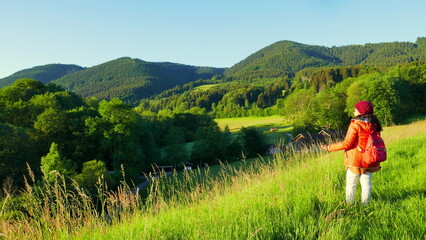 asiatische Touristin genießt Aussicht auf Wiesen und Berge im frühen Morgenlicht in Bayern beim...