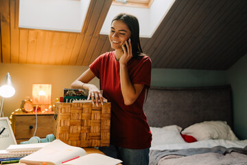 Young hispanic woman smiling and using cellphone at home